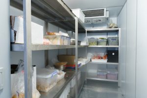 Refrigerator chamber with steel shelves in a restaurant close up