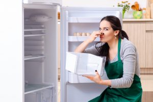 Young woman cleaning fridge in hygiene concept