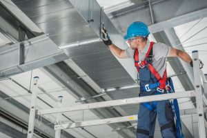 Professional Heating and Cooling Technician Worker Finishing Newly Assembled Air Vent Shaft. Air Climate Control and Filtering in Commercial Building.